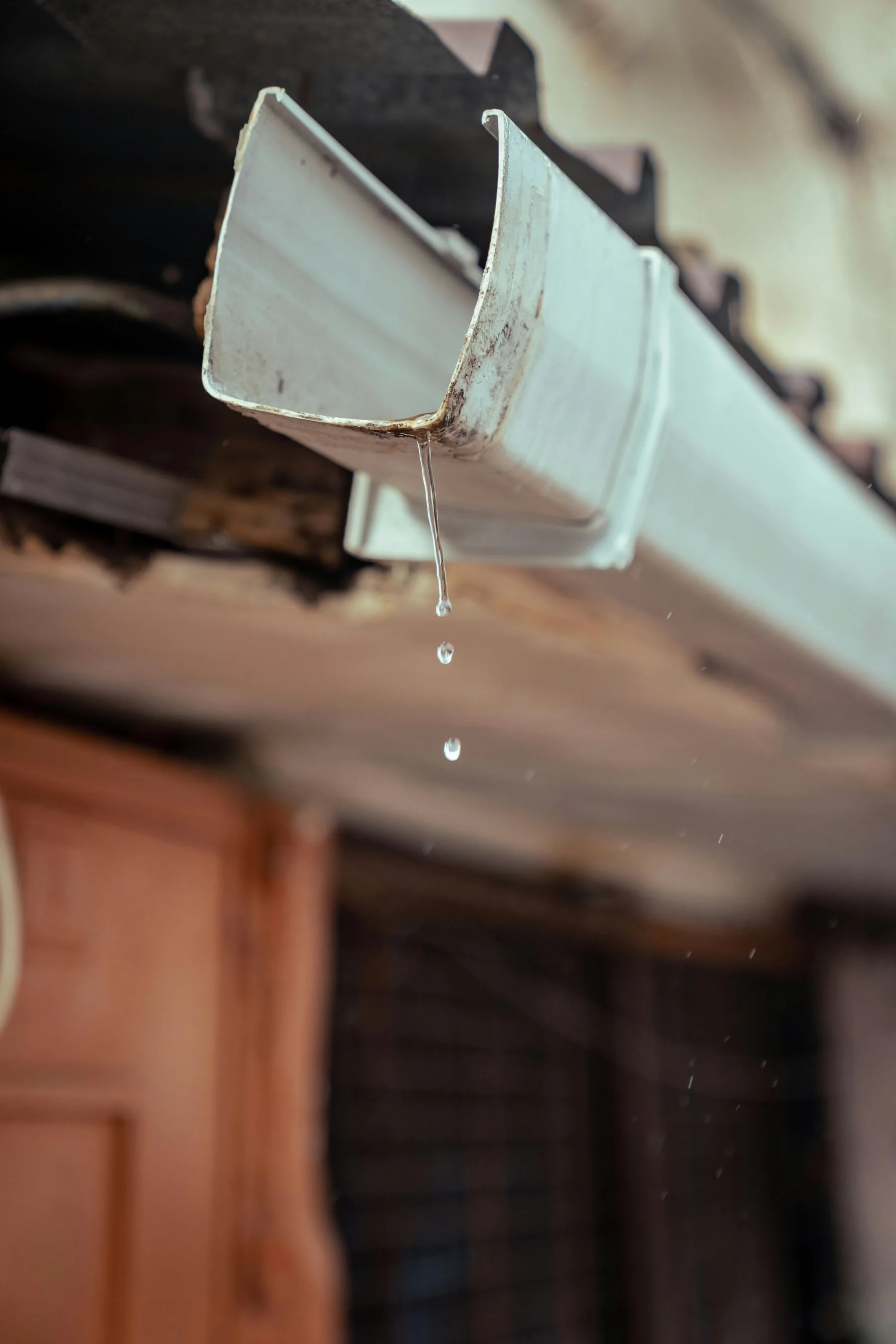 Close-up of water dripping from a house gutter.